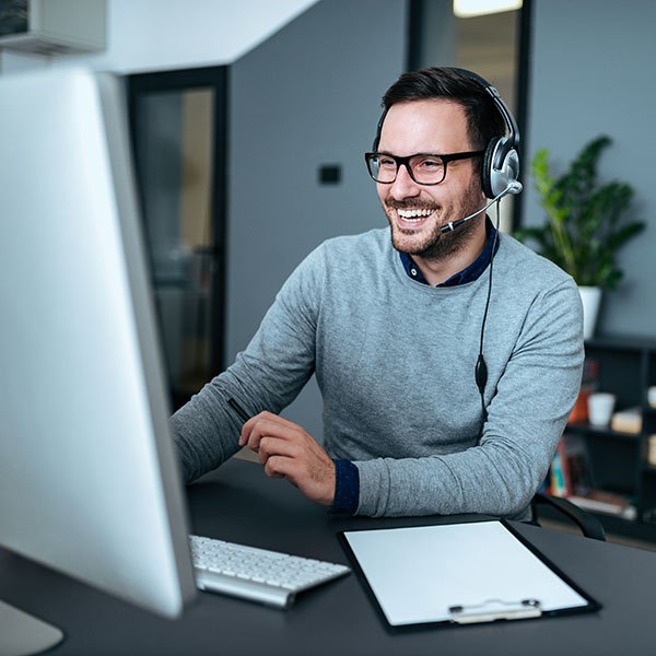 Portrait of a handsome smiling white man with headset working on the computer.